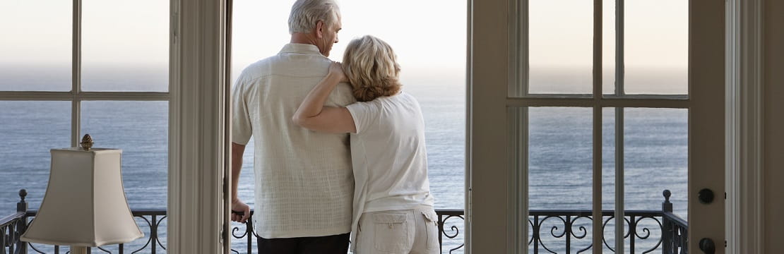 Couple looking at ocean view from balcony.